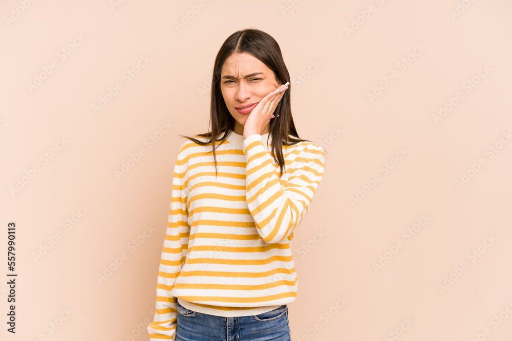 Young colombian woman isolated on beige background having a strong teeth pain, molar ache. Young colombian woman isolated on beige background having a strong teeth pain, molar ache.