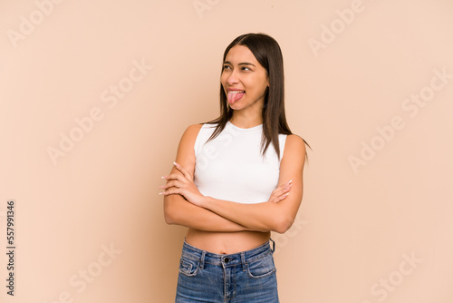 Young colombian woman isolated on beige background funny and friendly sticking out tongue. © Asier