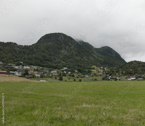 Landscape with the village at the foot of a mountain in Røldal, Norway. The mountain is covered with green trees and its peak is hidden by the fog.