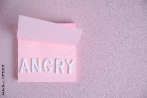 Word angry laid out white letters pink piece paper.Concept of anger, anger and discontent.