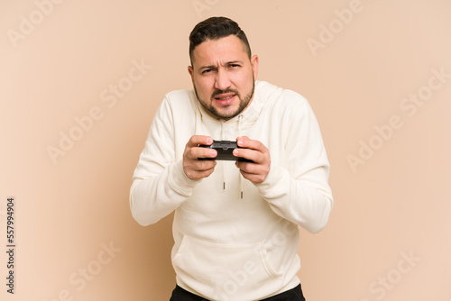 Adult latin man playing with a game controller isolated © Asier
