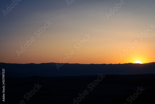 Dark horizon with orange sun glare at sunset in Death Valley national park in america