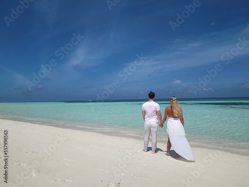 White dressed Honeymoon couple on the Malediven beach with White sand and blue ocean, Hochzeitsreise, Flitterwochen, Brautpaar am traumhaften Strand