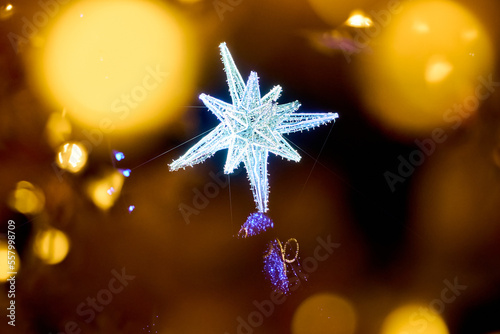 giant christmas star of led lights wrapped in golden glitter. close up bokeh surrounding christmas tree star at night. giant christmas tree on street. 