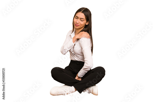 Young colombian woman sitting on the floor isolated having a shoulder pain. © Asier