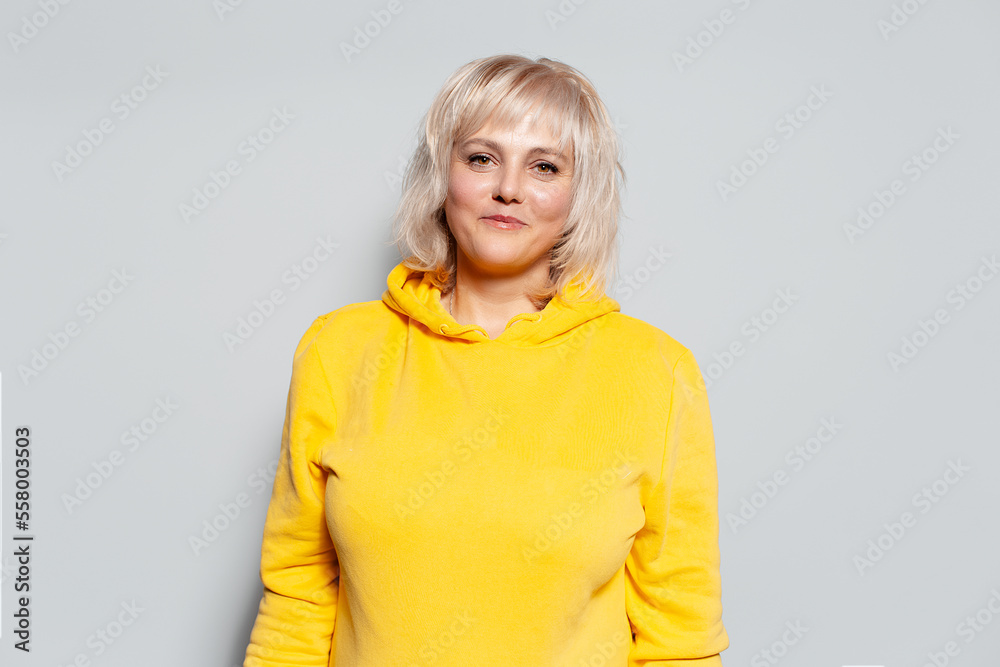Portrait of a smiling blonde woman, wearing yellow hoodie. Portrait of a smiling blonde woman, wearing yellow hoodie.