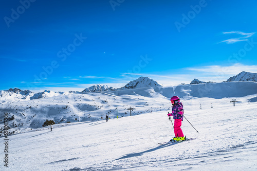 Young kid, girl skiing down on a ski slope. Sunny day on ski winter holidays in Andorra, El Tarter, Pyrenees Mountains