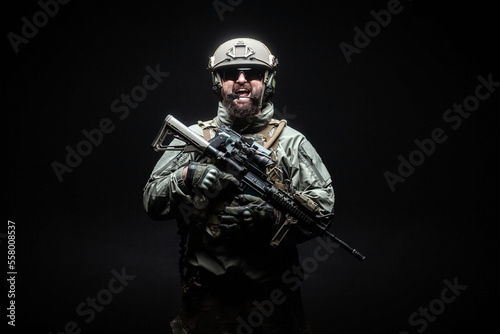 angry soldier in uniform with a rifle screaming at night, commando in stress on a black background, portrait of a ranger © Богдан Маліцький
