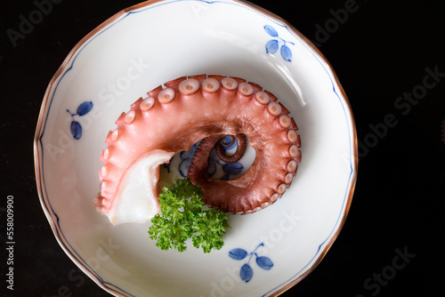 皿に載せた茹で蛸、ボイルしたタコ、蛸の切り身、茹でタコ、黒背景