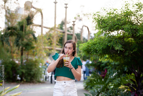 Beautiful tourist girl drinking a traditional Lulada at the Jairo Varela Square in the city of Cali in Colombia photo