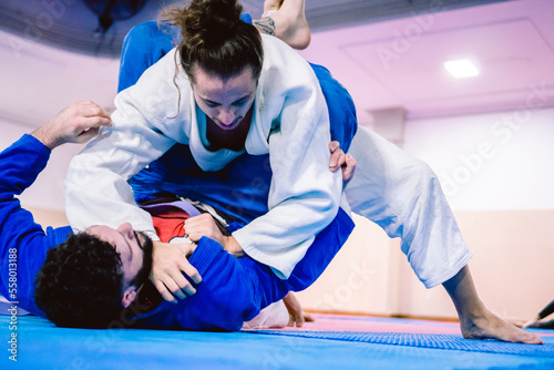 Young latino and hispanic man with a beard defending himself from the ground against his opponent in a jiu-jitsu practice.