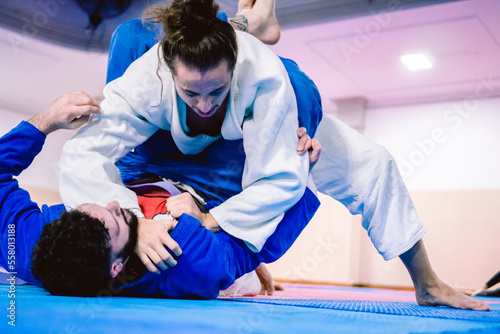 Young latino and hispanic man with a beard defending himself from the ground against his opponent in a jiu-jitsu practice. photo