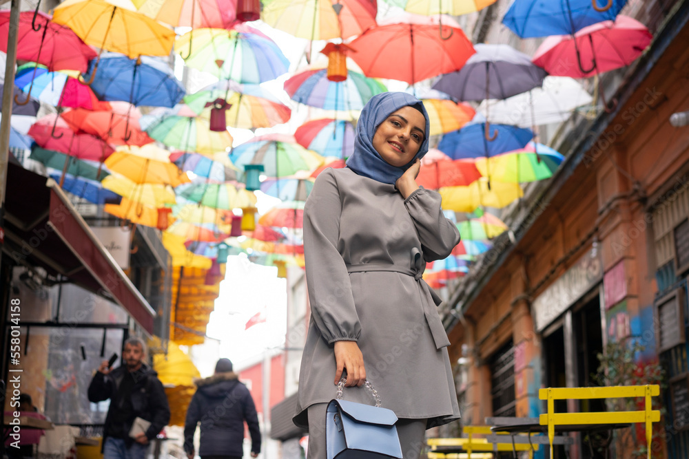 Girl in hijab, colorful umbrellas, sitting on chair. Young hijab girl ...