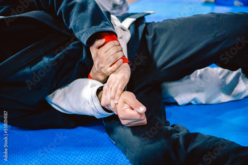 A man practicing jiu-jitsu defending himself from a lock being applied to him from behind.