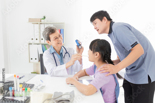 Doctor use tongue depressor and flashlight with children patient, he screening and diagnosis