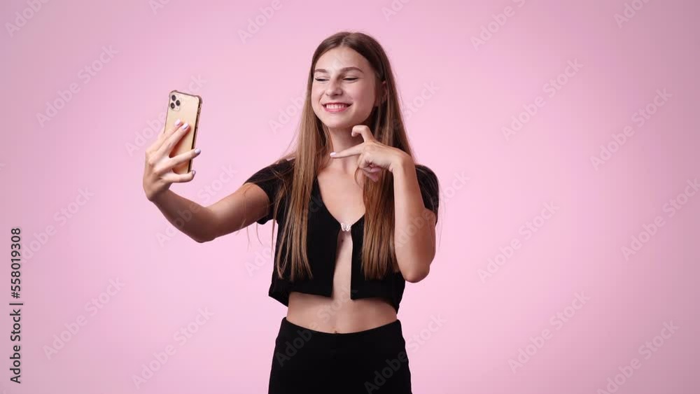 4k slow motion video of cute girl using phone and waving hello over pink background. 4k slow motion video of cute girl using phone and waving hello over pink background.