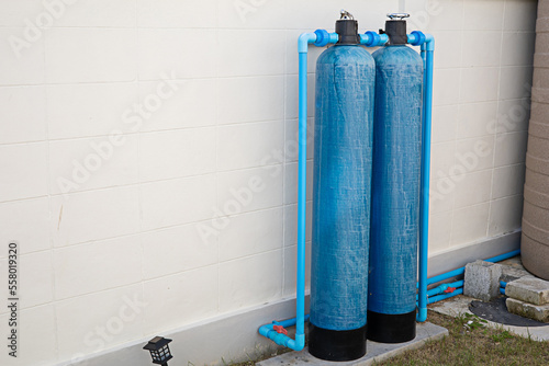 The water filter tank is installed on the wall of the fence of the house.
