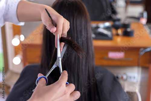 Professional hairdresser cutting woman's hair in beauty salon, closeup