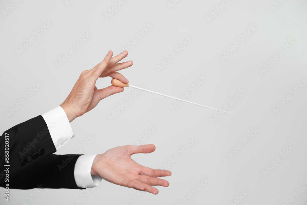 Professional conductor with baton on light grey background, closeup. Space for text - obrazy, fototapety, plakaty 