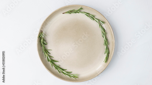 beige plate stands on a gray background close up. wreath of fresh rosemary on a plate. minimalist concept, copy space, space for text 