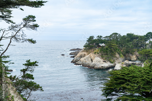 California, USA - May 19, 2018: beautiful seascape and skyline of big sur along California highway one with cypress trees and houses at sea shore on cloudy day