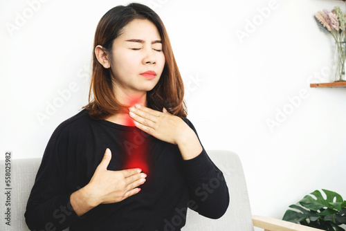 Asian woman suffering from acid reflux or gastroesophageal reflux disease (GERD) feeling uncomfortable and burning chest move up to neck and throat photo