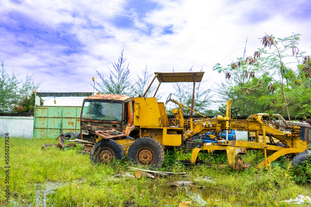 Views from the multiple kind of vehicles broken down focused on an old tractor with the plants start to grow around them, at a park Views from the multiple kind of vehicles broken down focused on an old tractor with the plants start to grow around them, at a park
