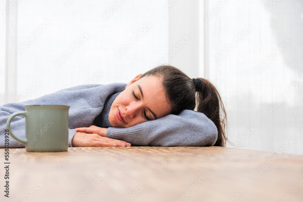 Girl falls asleep at the table with a cup of coffee