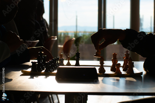 Two old hands playing chess on a table with chronometer