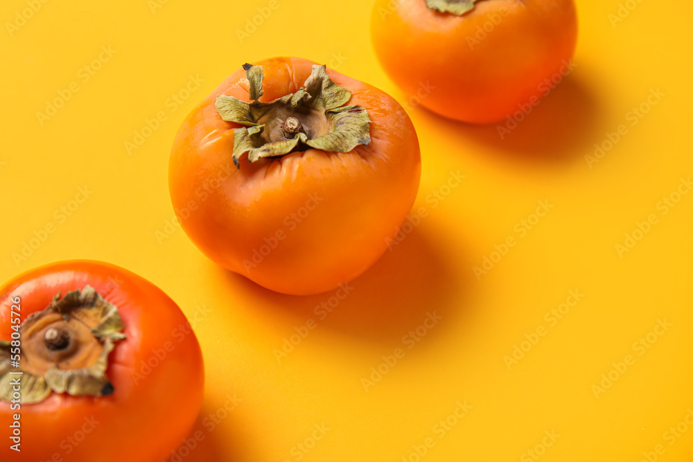 Fresh ripe persimmons on color background, closeup Fresh ripe persimmons on color background, closeup