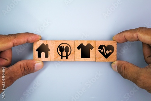 wooden cube with icons of food, Clothing, housing, medicine, four basic human needs concepts. Four Basic Human Material Needs. photo