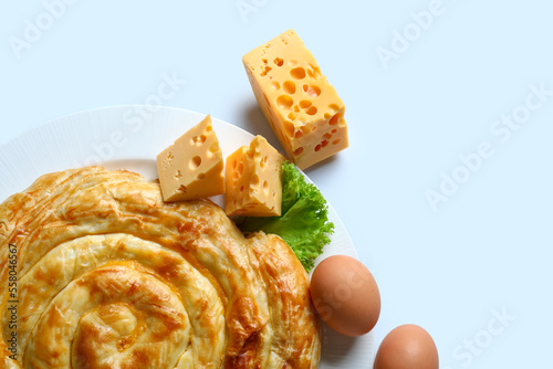 Plate with delicious cheese pie and ingredients on blue background photo