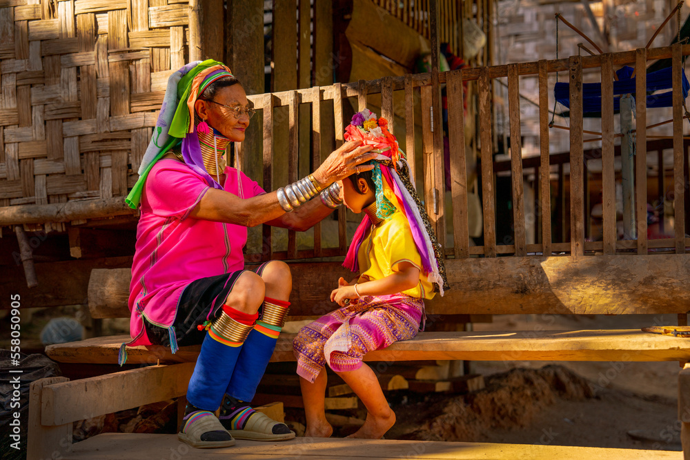 Ταπετσαρία Old woman as grand mother of little girl help to set and decorate hair style of the girl in Long Neck Karen Village in Thailand