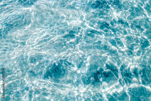 Crystal clear water. Background of blue and clear sea water with bright highlights on the waves.