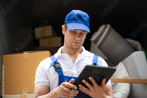 Moving service workers outdoors, unloading boxes and checking list is coming to deliver items to the family moving house.