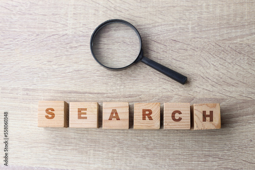 Wooden blocks form the word search and magnifying glass on a wooden background. Search Engine Optimization concept.