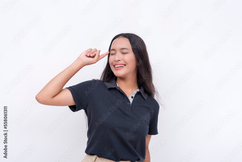 A young asian woman feeling euphoric after realizing the solution. Pointing her finger to the temple. Isolated on a white background. A young asian woman feeling euphoric after realizing the solution. Pointing her finger to the temple. Isolated on a white background.