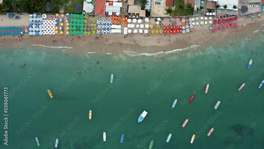 Bird's eye top-down aerial moving shot of the famous Porto de Galinhas or Chicken Port beach in Pernambuco, Brazil with hotels, colorful umbrellas, tourists swimming in the natural pools and sailboats Bird's eye top-down aerial moving shot of the famous Porto de Galinhas or Chicken Port beach in Pernambuco, Brazil with hotels, colorful umbrellas, tourists swimming in the natural pools and sailboats