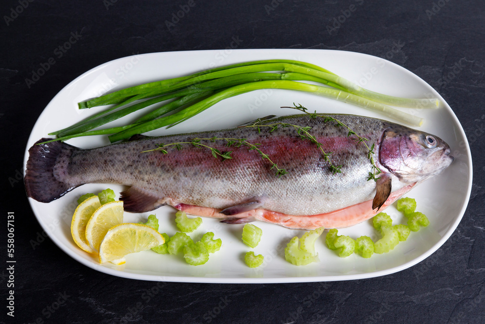 Fresh rainbow trout with fresh vegetables on white plate. Healthy lifestyle, mediterranean diet.