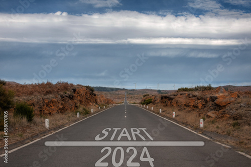 Start 2024 year road sign on a country road with wind electricity plants in the background as a concept of renewable energy friendly year photo