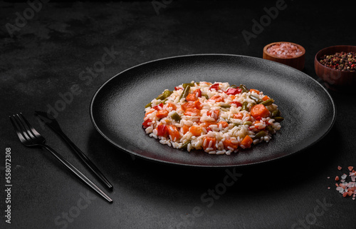 Delicious fresh risotto with vegetables, spices and herbs on a black plate