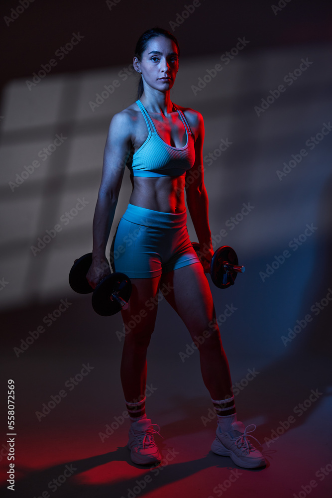 Fitness woman model with great body working out in red blue toning light