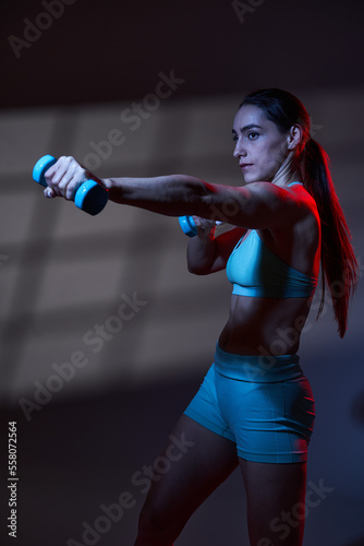 Fitness woman model with great body working out in red blue toning light