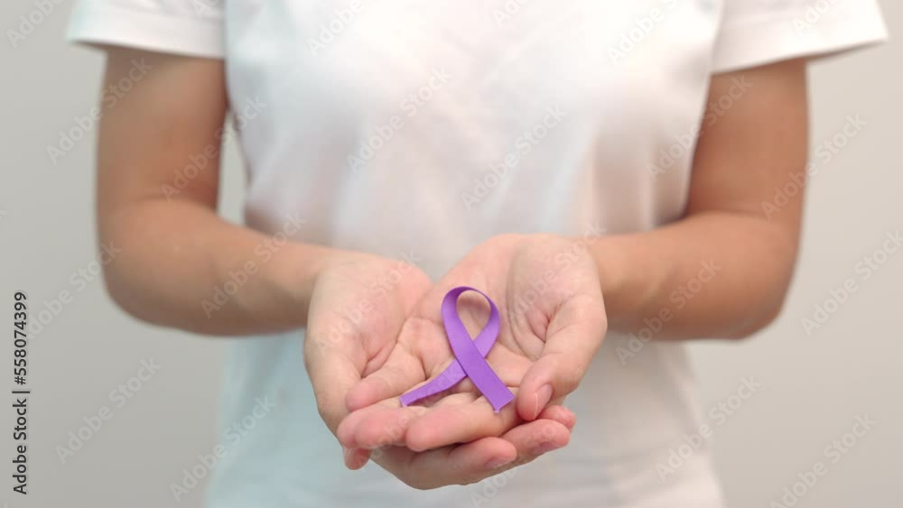 Hand holding purple Ribbon for Pancreatic, Esophageal, Testicular cancer, world Alzheimer, epilepsy, lupus, Sarcoidosis, Fibromyalgia and domestic violence Awareness month. World cancer day concept Hand holding purple Ribbon for Pancreatic, Esophageal, Testicular cancer, world Alzheimer, epilepsy, lupus, Sarcoidosis, Fibromyalgia and domestic violence Awareness month. World cancer day concept