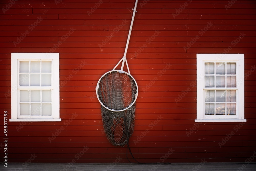 A decorative brailer on a red wooden wall of a house