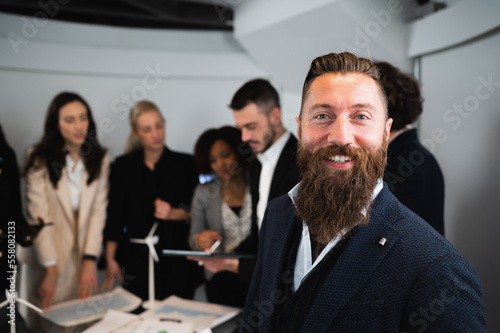 portrait of smiling hipster businessman in elegant suits with defocused teamwork in background.