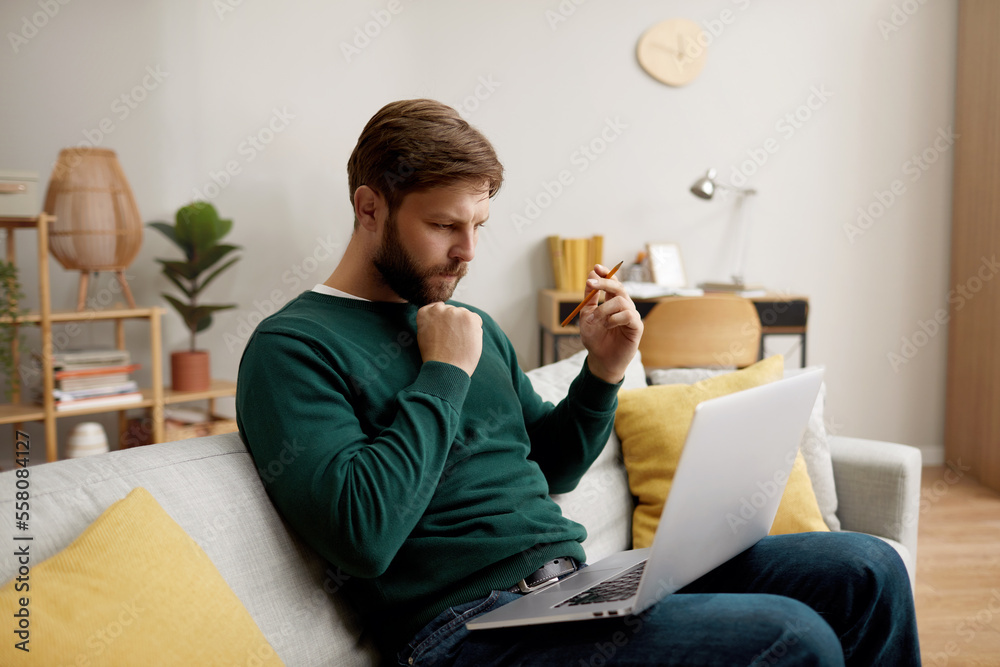 Focused Man Working Laptop. Handsome Young Man Using Laptop Computer At Home. Student Men Working Room. Online Shopping, Home Work, Freelance, Online Learning, Studying Concept