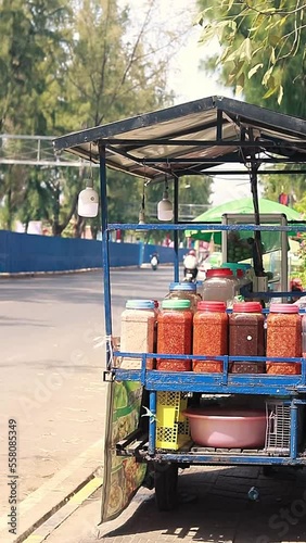 Vertical video of a food cart or brohet park on the roadside and filled with spicy dipping sauce for mju, a popular khmer streetfood of fermented and fresh mix fruits photo