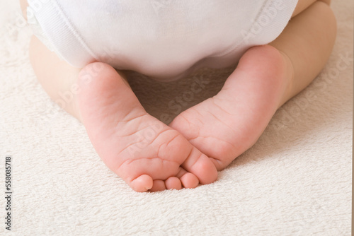 Cute baby feet on light beige home carpet. Back view. 5 to 6 months old infant. Barefoot closeup. photo