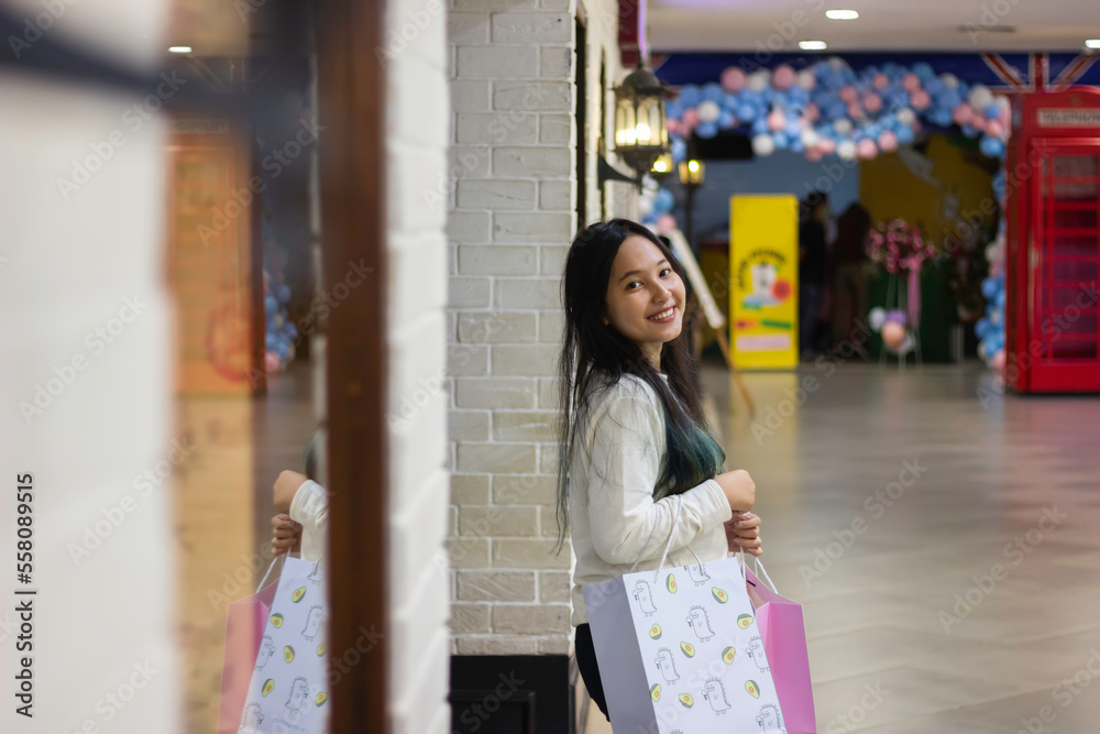 Young asian woman smiling and brings shopping bags spending time in shopping mall Young asian woman smiling and brings shopping bags spending time in shopping mall